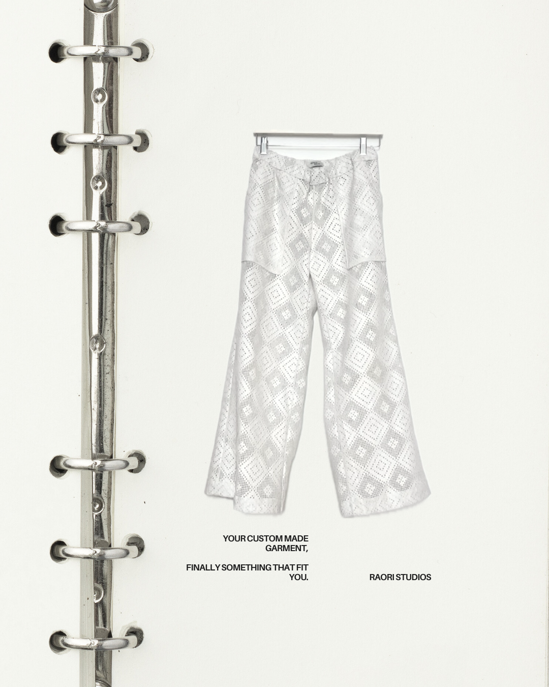 White pants with geometric pattern hanging on a rack against a white background